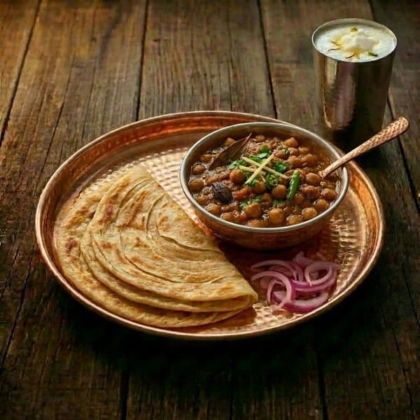 Laccha paratha with chole and lassi on a copper thali